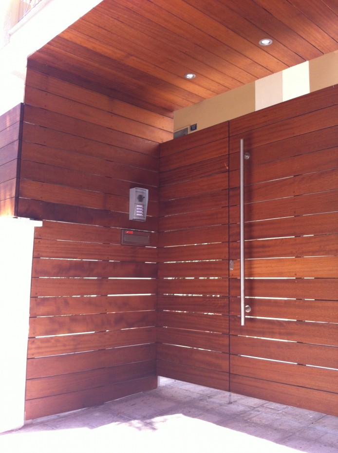 Περίφραξη, γκαραζόπορτα και πόρτα εισόδου με οριζόντιες λείες σανίδες iroko